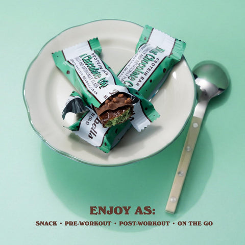 Baton proteinowy Guiltfree Barebells Mint Chocolate Crisp na talerzyku z łyżeczką, przekrojony na pół