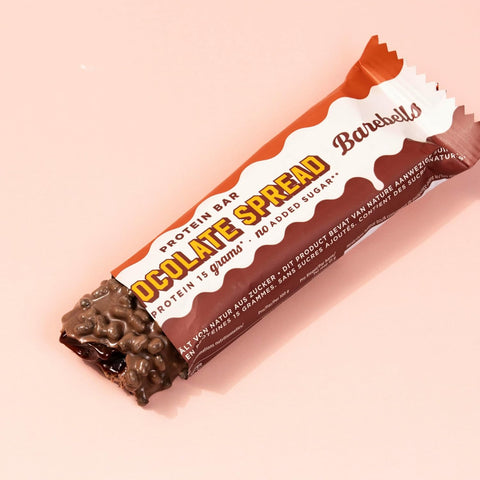 Guiltfree baton proteinowy Barebells Chocolate Spread w mlecznej czekoladzie z chrupiącymi kawałkami na różowym tle