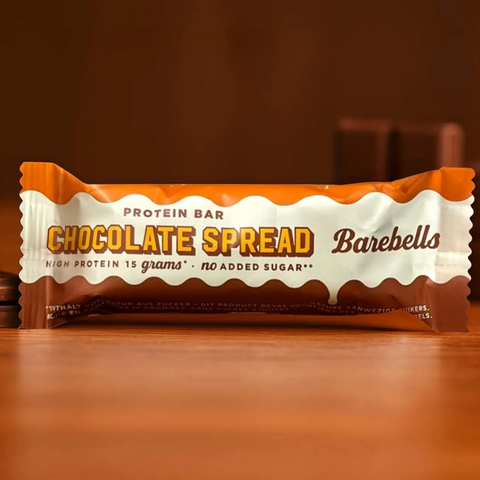 Guiltfree baton proteinowy Barebells Chocolate Spread w pomarańczowo-brązowym opakowaniu na drewnianym stole