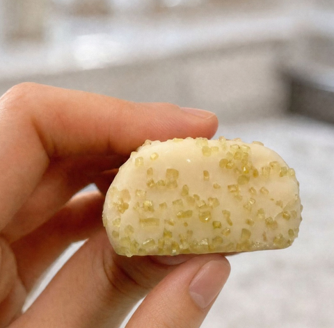 Guiltfree baton proteinowy Sour Puff Green Apple Crush z białą polewą i chrupiącą zieloną posypką trzymany w dłoni