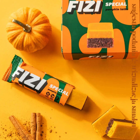 Wegański baton Guiltfree FIZI Pumpkin Latte z dynią i cynamonem obok małej dyni i lasek cynamonu na żółtym tle