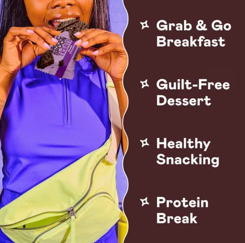 Kobieta je baton proteinowy Guiltfree Magic Spoon Double Chocolate w fioletowej koszulce z nerką na biodrach.