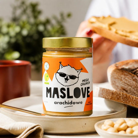 Masło orzechowe Guiltfree Maslove Mega Crunch w szklanym słoiku z widocznymi kawałkami orzechów na stole śniadaniowym