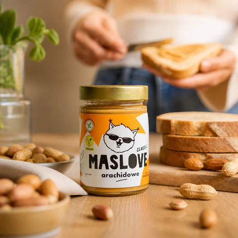 Guiltfree Maslove gładkie masło orzechowe 100% arachidów w szklanym słoiku na drewnianym stole z orzechami w tle