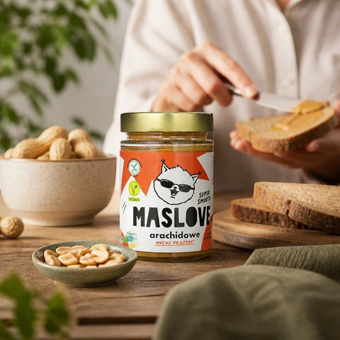 Guiltfree Maslove masło orzechowe super smooth w szklanym słoiku na drewnianym stole z orzeszkami i kromką chleba