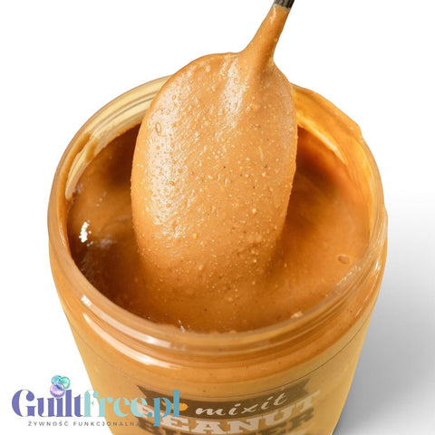 Guiltfree Mixit masło orzechowe smooth w plastikowym słoiku z łyżką nabierającą kremową masę na żółtym tle