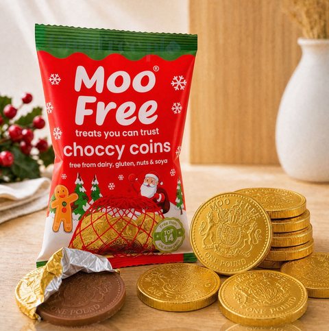 Wegańskie czekoladowe monety Moo Free w złotej folii obok świątecznego opakowania od Guiltfree