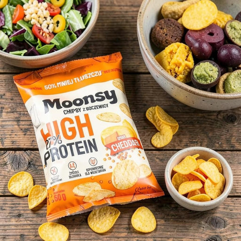 Opakowanie chipsów soczewicowych Guiltfree Moonsy High Protein o smaku sera cheddar na drewnianym stole z sałatką