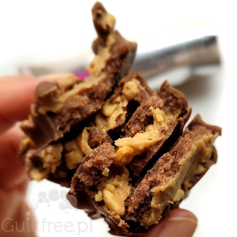 Przełamany baton proteinowy N!ck's Peanut Butter z Guiltfree z widoczną masą orzechową i kawałkami orzechów w czekoladzie