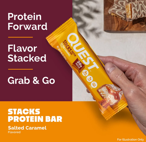 Guiltfree baton proteinowy Quest Stacks Salted Caramel w żółtym opakowaniu trzymany w dłoni na tle deski z batonem
