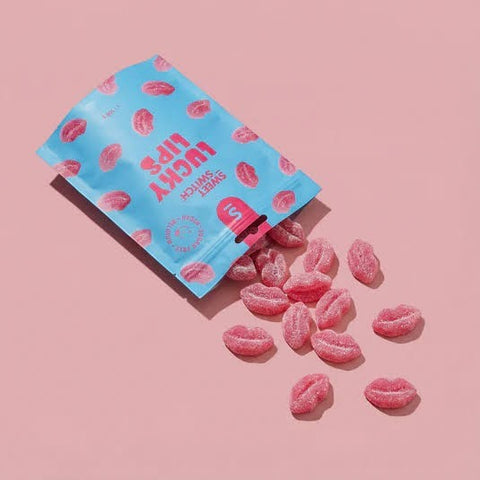 Wegańskie żelki Guiltfree Sweet Switch Lucky Lips w kształcie różowych ust o smaku malinowym wysypane z opakowania.