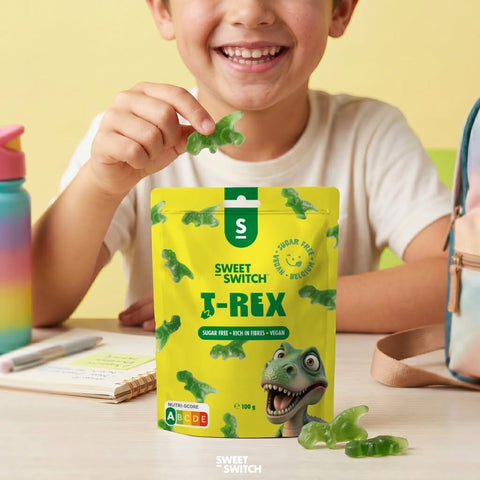 Dziecko trzyma zielonego żelka dinozaura Sweet Switch T-Rex obok opakowania wegańskich słodyczy bez cukru marki Guiltfree