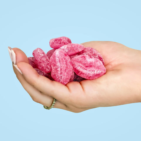 Dłoń trzymająca różowe wegańskie żelki Sweet Switch Lucky Lips w kształcie ust o smaku malinowym bez cukru