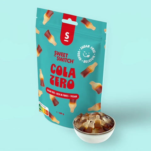Wegańskie żelki Sweet Switch Cola Zero w kształcie buteleczek w miseczce obok opakowania, oferta Guiltfree.